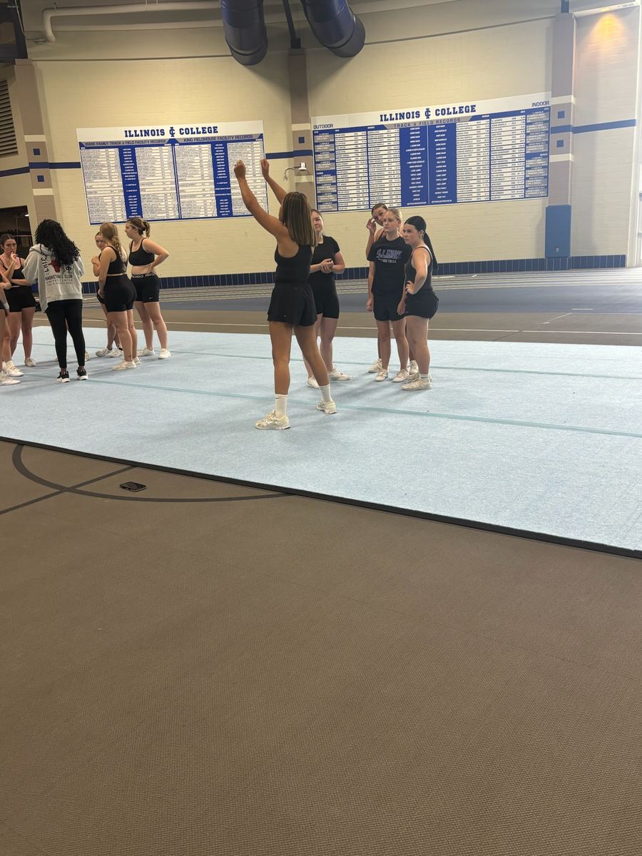 A coach demonstrating a motion to a group of cheer athletes
