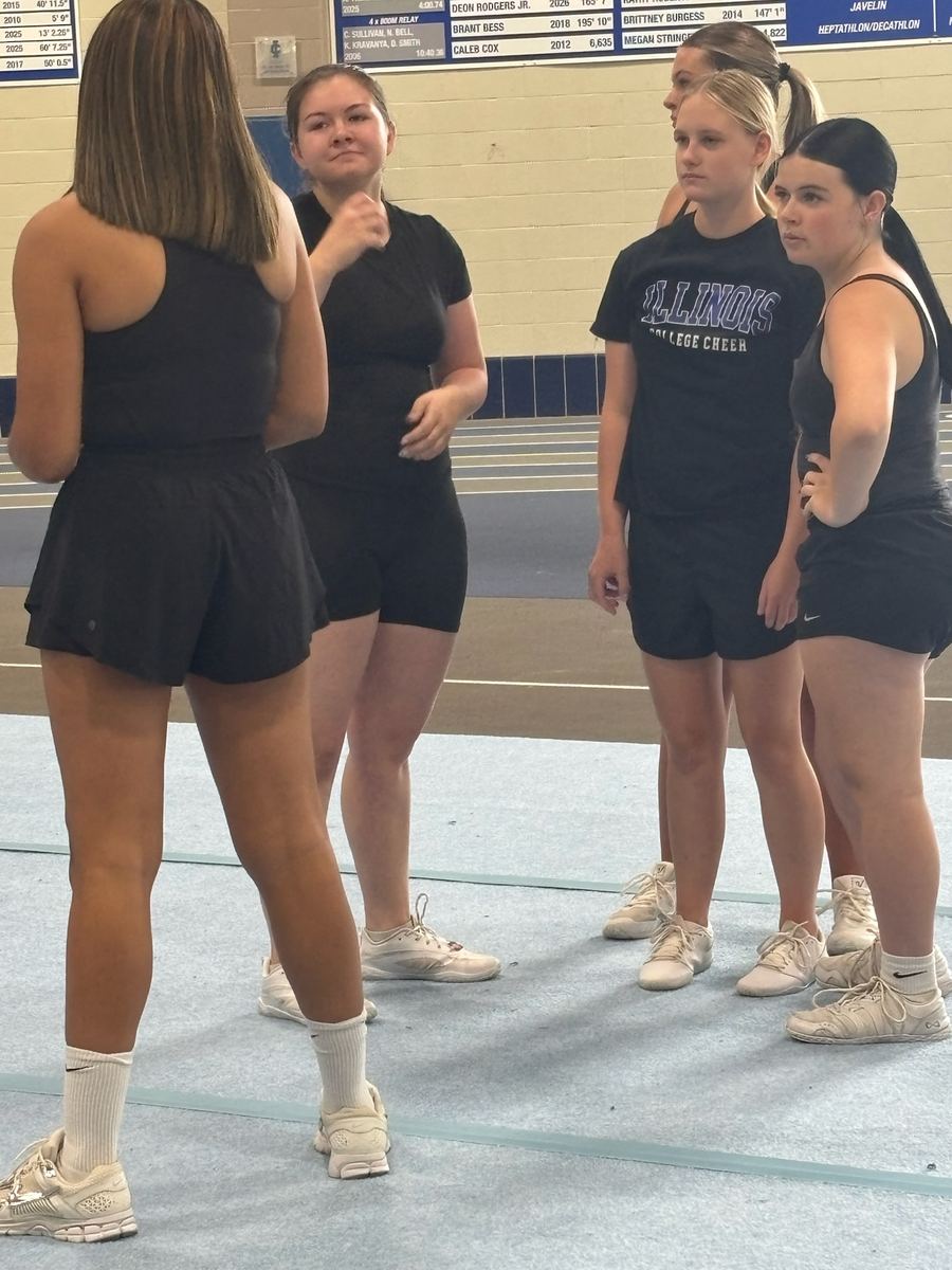 Cheer athletes standing in a group listening during a clinic