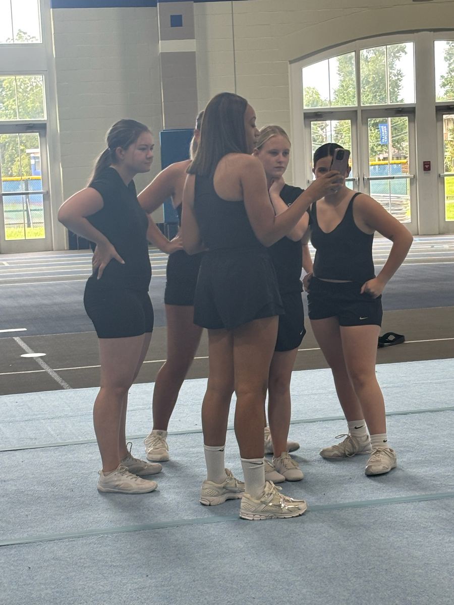 A small group of cheer athletes in a huddle during a skill block